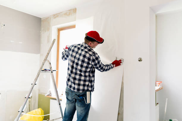 Glueing wallpapers at home. Young man, worker is putting up wallpapers on the wall. Home renovation concept stock photo