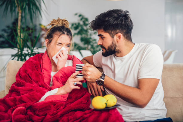 istock Handsome man taking care of his sick girlfriend lying on the sofa 954924732