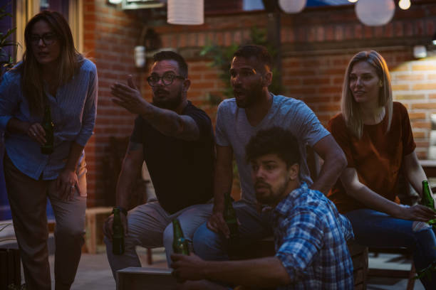 istock Friends Watching Sports On Big Screen In Backyard 954928360