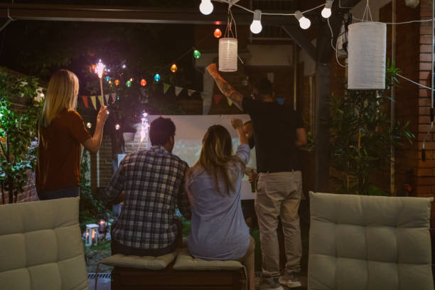 istock Friends Watching Soccer Game On Big Screen In Backyard 954928870