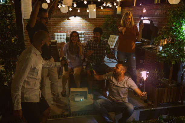 istock Friends Watching Sports On Big Screen In Backyard 954928978