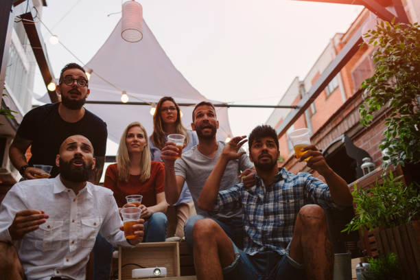istock Friends Watching Sports On Big Screen In Backyard 954931926
