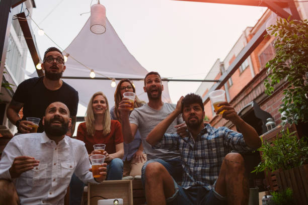 istock Friends Watching Sports On Big Screen In Backyard 954931958