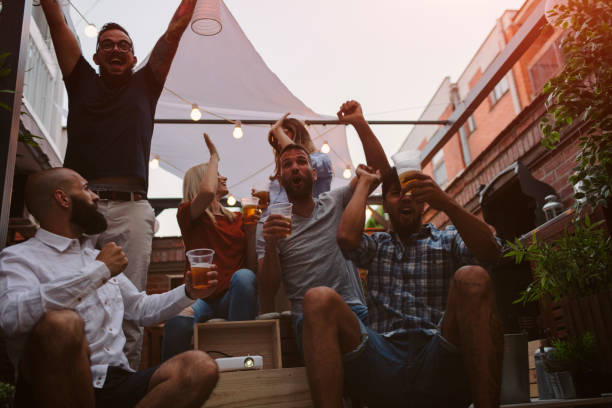 istock Friends Watching Sports On Big Screen In Backyard 954932444