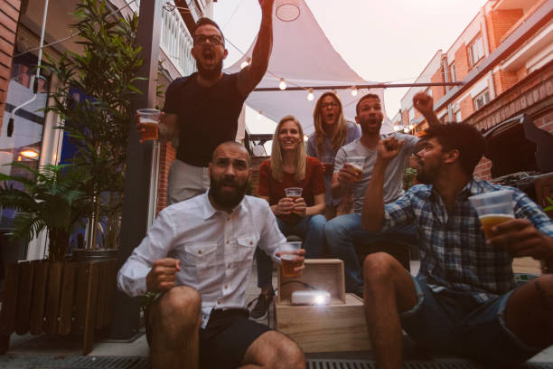 istock Friends Watching Sports On Big Screen In Backyard 954932882