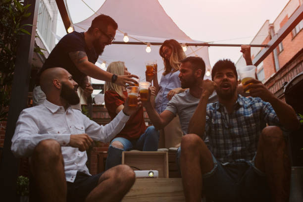 istock Friends Watching Sports On Big Screen In Backyard 954933200
