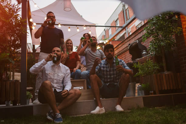 istock Friends Watching Sports On Big Screen In Backyard 954933434