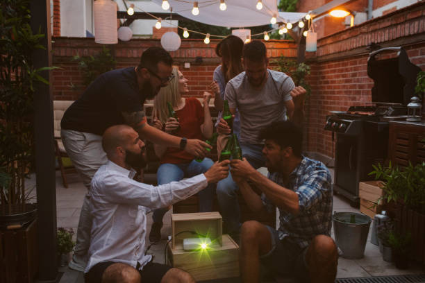 istock Friends Watching Sports On Big Screen In Backyard 954933564