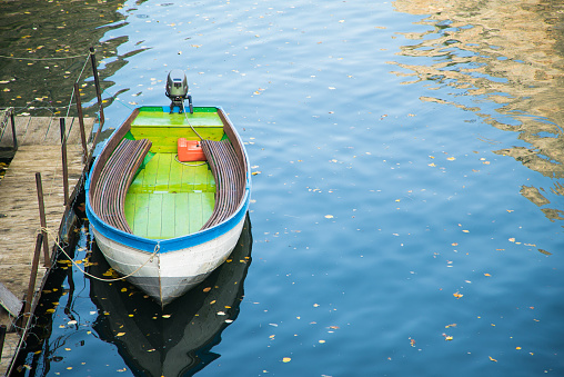 Small colorful fishing boat anchored at the lake jetty.