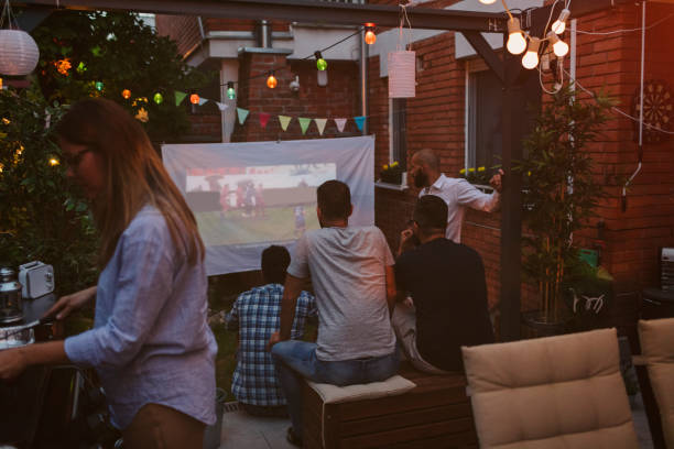 istock Friends Watching Sports On Big Screen In Backyard 954933678