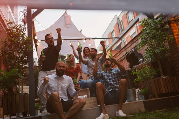 istock Friends Watching Sports On Big Screen In Backyard 954933776