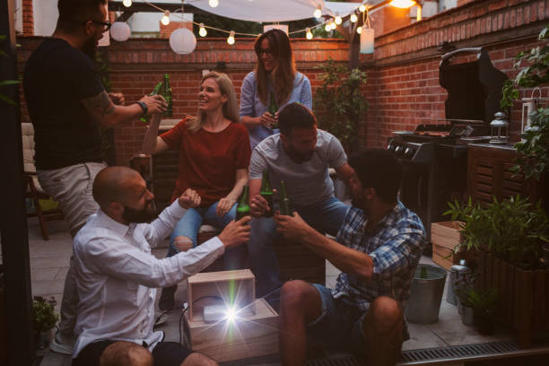 istock Friends Watching Sports On Big Screen In Backyard 954933778