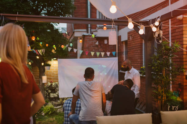 istock Friends Watching Sports On Big Screen In Backyard 954934092