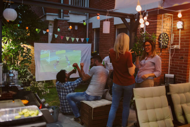 istock Friends Watching Sports On Big Screen In Backyard 954936270