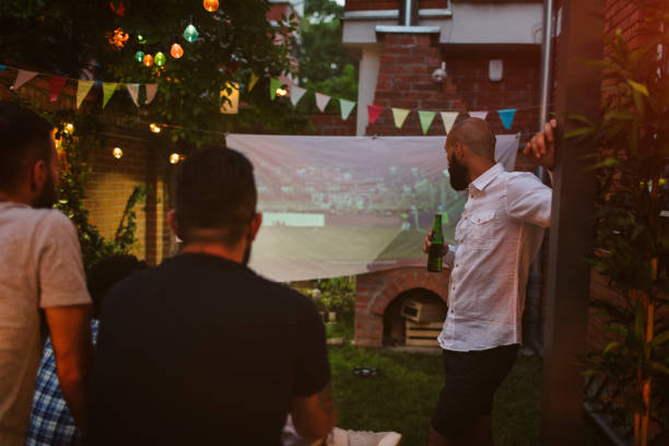 istock Friends Watching Sports On Big Screen In Backyard 954936444