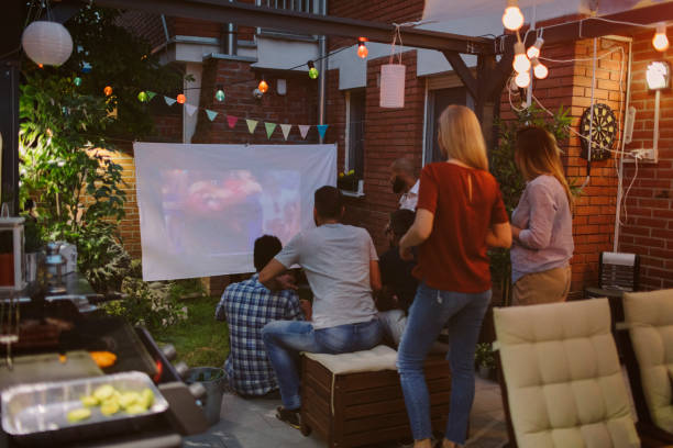 istock Friends Watching Sports On Big Screen In Backyard 954936618