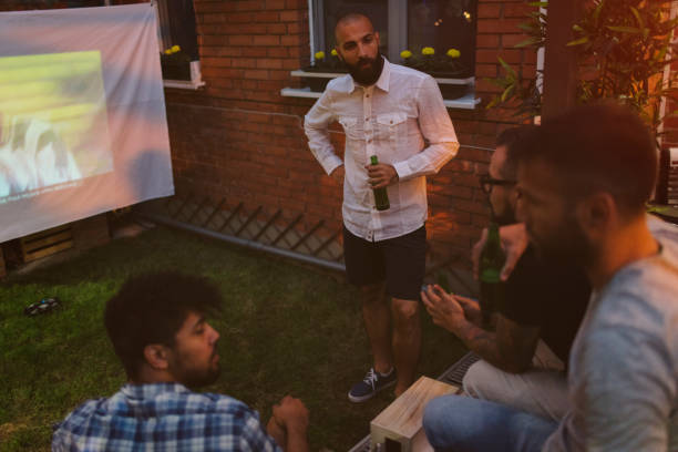 amis, regarder les sports sur grand écran dans l’arrière-cour - barbecue foot photos et images de collection