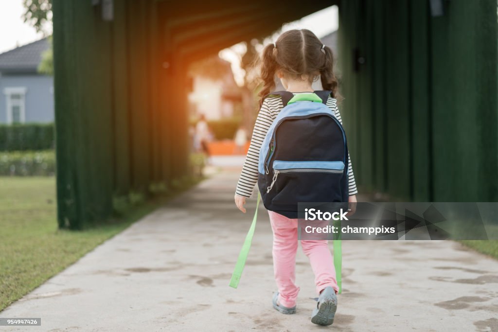 Kid girl pupil walking back to home after learning study school alone with schoolbag,preschool and kindergarten education concept. Child Stock Photo