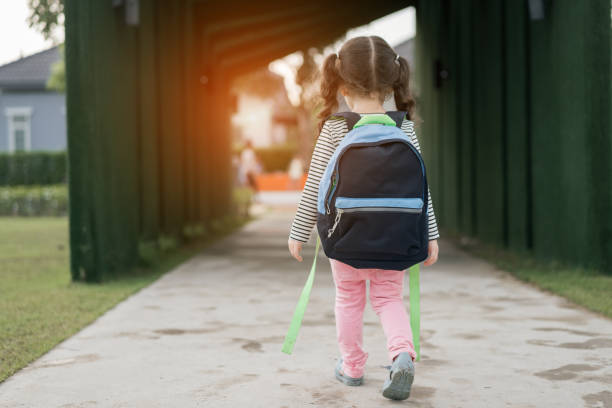 pupila de menina criança andando de volta para casa após estudo escola sozinha com o conceito de educação com a mochila, pré-escola e jardim de infância de aprendizagem. - back school - fotografias e filmes do acervo