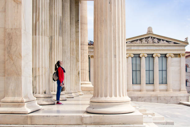 una ragazza guarda il soffitto, sotto le colonne dell'accademia ateniese - philosopher foto e immagini stock