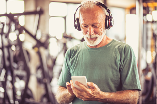 Senior man at gym listening music.
