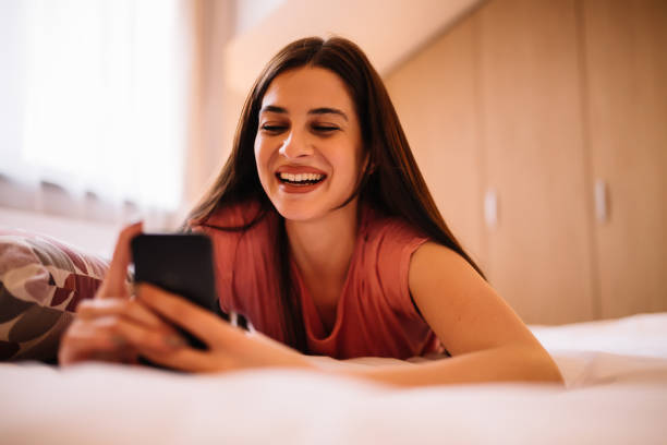 istock Happy girl using a mobile phone lying on the bed at home 954961938