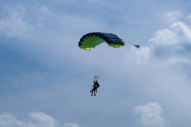 Reggio Emilia, Italy - May 2017: Parachutists: Instructor and Beginner with Blue Parachute preparing for Landing in Summer Day near Reggio Emilia airport