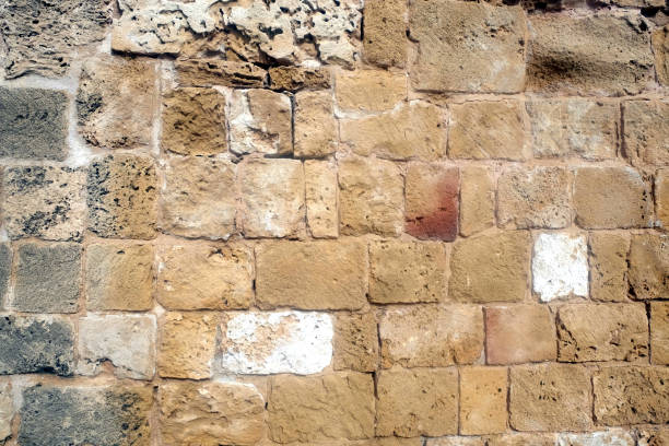 istock Ancien wall from brown stones front view close up 954975868