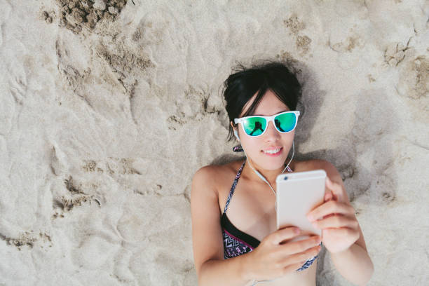 mujer escuchando música en la playa - asian cuisine audio fotografías e imágenes de stock