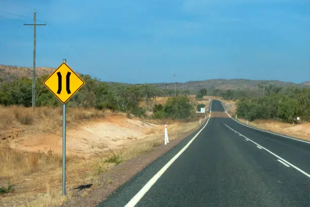 Photo of Road narrows sign near road in the outback of Queensland in Australia