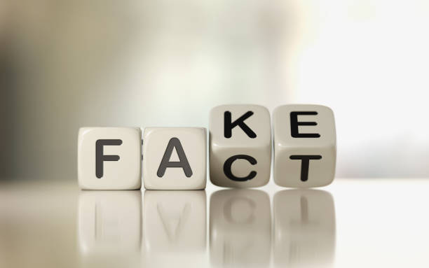 Fake News Concept White toy blocks are rotating on white reflective surface over pale defocused background.  Fake and fact writes on the cubes. Fake news concept. Horizontal composition with copy space. fake news stock pictures, royalty-free photos & images