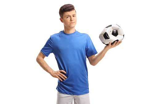 Sad teenage soccer player holding a deflated football isolated on white background