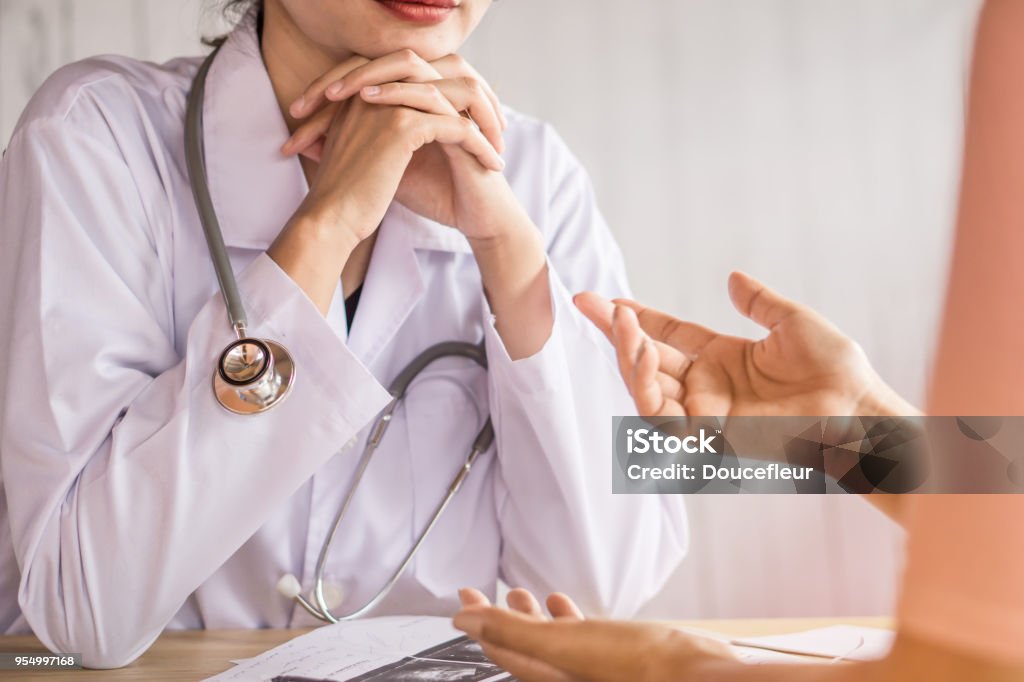 female doctor listening to depressed patient talking at hospital female doctor listening to depressed patient talking about health problem at a hospital Female Doctor Stock Photo