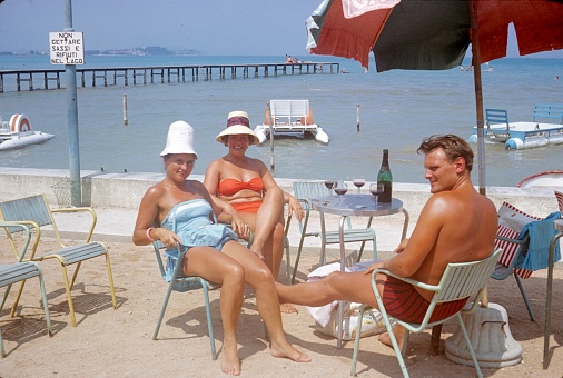 Lake Como, Lombardy, Italy, 1964. Tourists relax with a bottle of wine on a restaurant terrace on Lake Como.