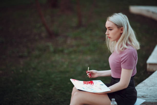 istock Young pretty woman painter draw in park 955023624