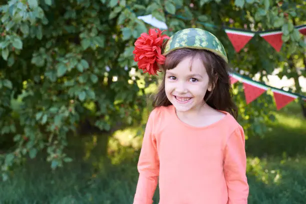Small child. Pretty Girl. Watermelon on the head. Brightly colored flower.