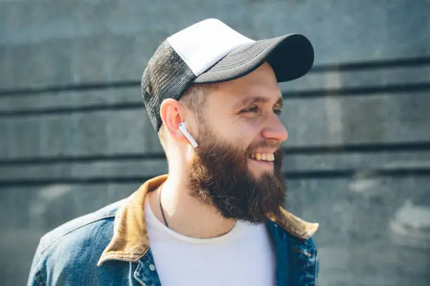 Hipster man with sport in-ear wireless headphones listening to music and using a tablet pc