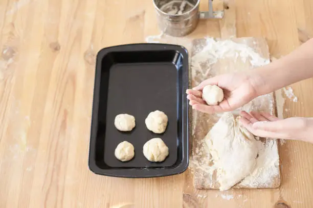 Raw dough. Black pan. Cooking buns. Delicious recipe.
