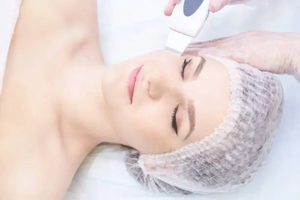 Ultrasonic cleaning of the face. Young girl. Modern equipment. Cosmetic procedure.