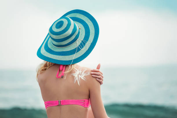 istock Young woman on beach applying sun block creme 955033806