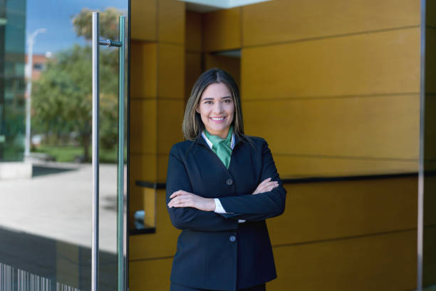 Latin american female hotel manager standing at the entrance with arms crossed looking at camera very happy Latin american female hotel manager standing at the entrance with arms crossed looking at camera very happy and smiling hotel reception hotel business lobby stock pictures, royalty-free photos & images