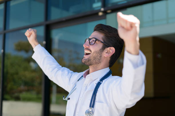 Excited young doctor celebrating with arms up