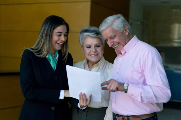 istock Friendly senior couple asking beautiful hotel hostess for help with tourism information all smiling 955036362