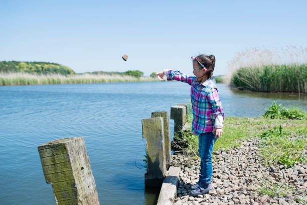 Little girl who throws a stone in a pond