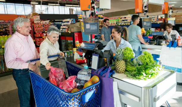 clientèle supérieurs leur épicerie dans un supermarché et sympathique vendeuse aidant avec la caisse - supermarket discussion people talking photos et images de collection