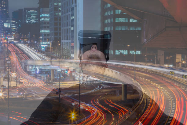istock Man wearing a virtual reality headset and viewing night cityscape 955051940