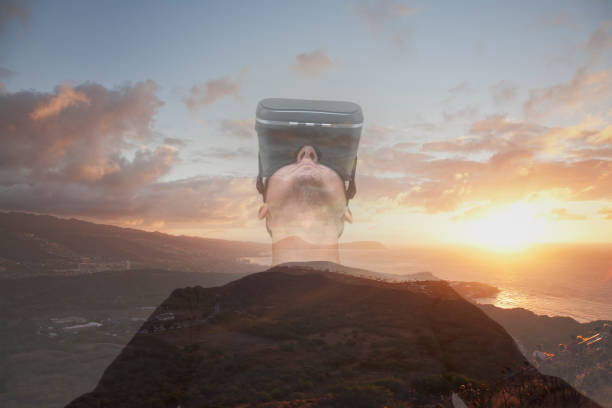 istock Man wearing a virtual reality headset and viewing the scenery at dawn from the Diamond Head in a virtual reality world 955056808