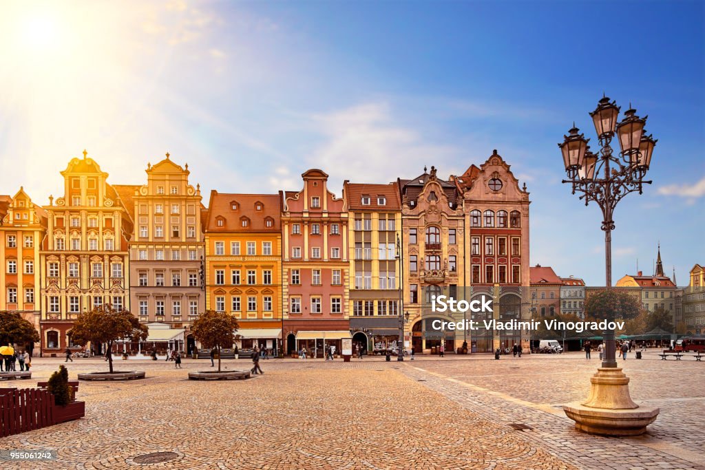 Central market square in Wroclaw Poland with old colourful houses, street lantern lamp and walking tourists people at gorgeous stunning morning sunrise sunshine. Travel vacation concept Central market square in Wroclaw Poland with old colourful houses, street lantern lamp and walking tourists people at gorgeous stunning morning sunrise sunshine. Travel vacation concept. Krakow Stock Photo