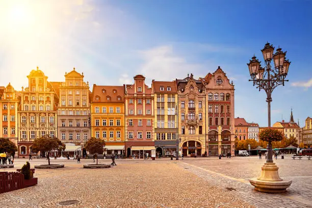 Central market square in Wroclaw Poland with old colourful houses, street lantern lamp and walking tourists people at gorgeous stunning morning sunrise sunshine. Travel vacation concept.