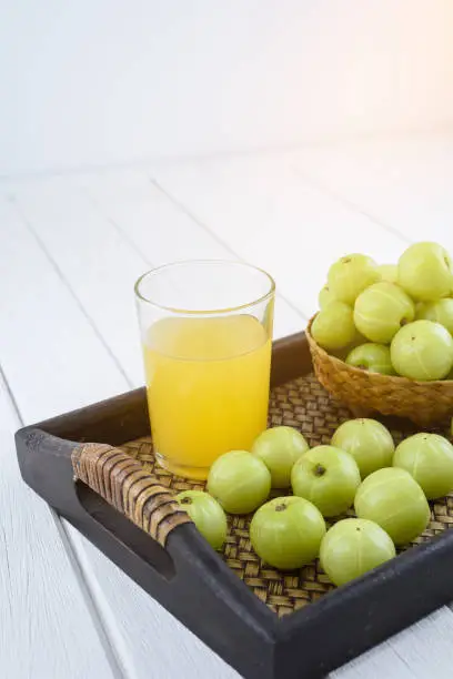 Indian gooseberry in Wooden Tray and juice on white wooden table